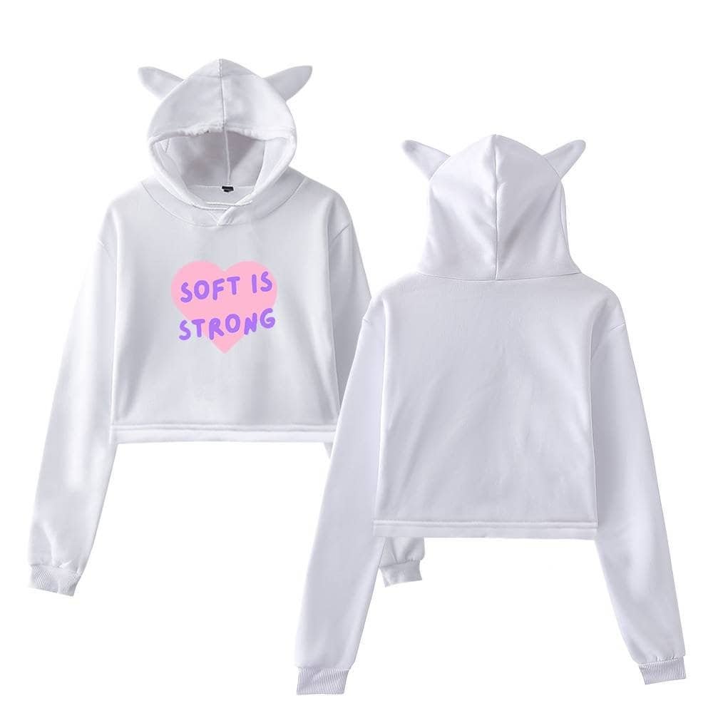 White hoodie with bunny ears and "Soft is Strong" slogan in pink and purple text on the front.