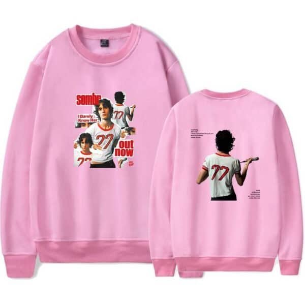 Sublimated pink sweatshirt with graphic print of a girl holding a microphone, featuring the text "sombout now" and "I Barely Know Her" in bold letters, casual streetwear style, affordable high-quality merchandise.