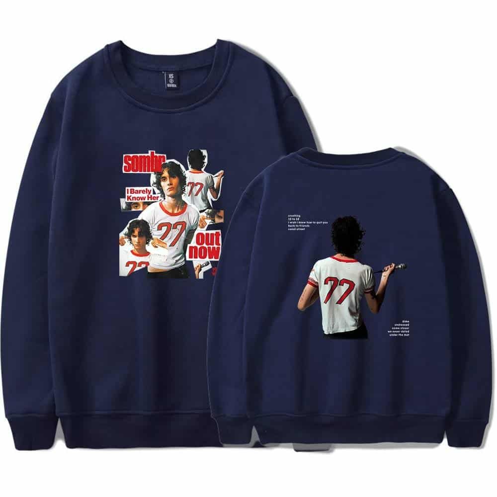 Sweatshirt featuring a graphic design with a woman holding a microphone and the text "somb" and "out now," in navy blue color.